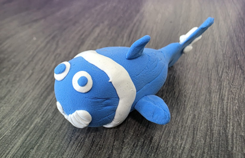 Blue clay fish model displayed on a wooden table.