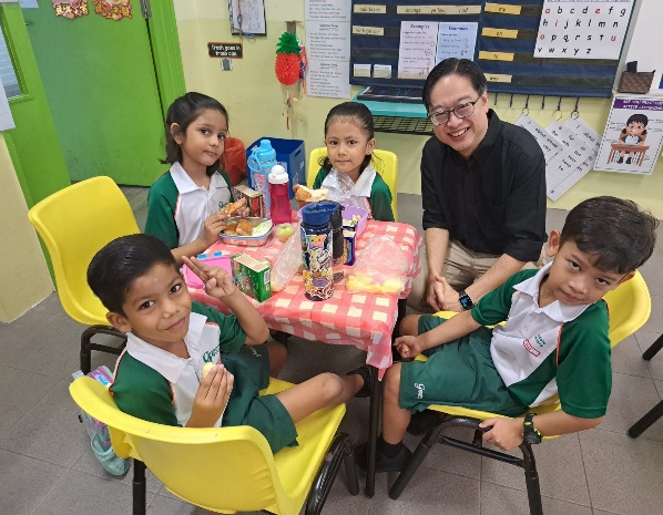 Principal sharing a meal with students during a classroom lunch session.