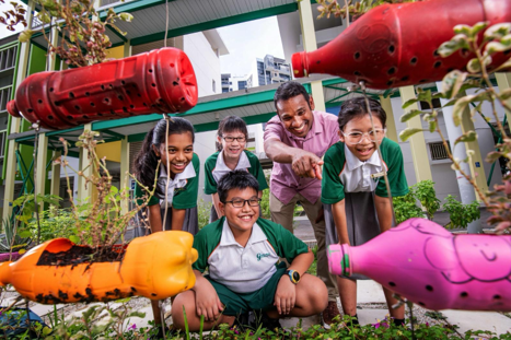 Teacher and students examining plants together in a school garden learning space.